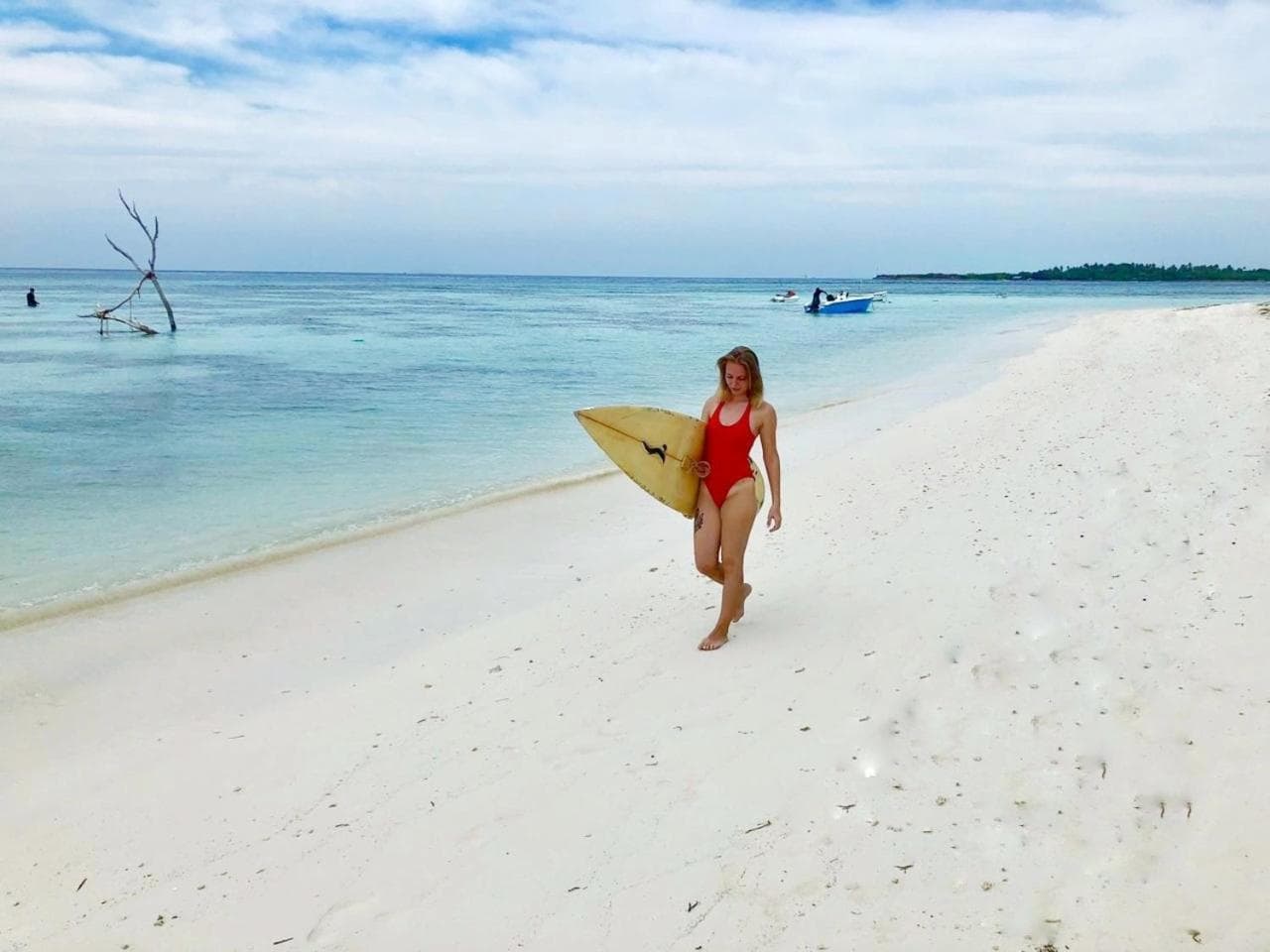 Surfer walking Himmafushi beach with a board under her arm