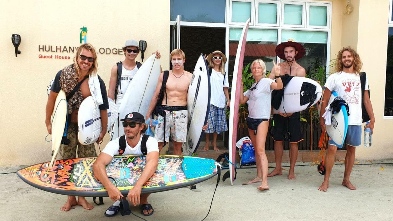 Group of surfers with boards outside the lodge
