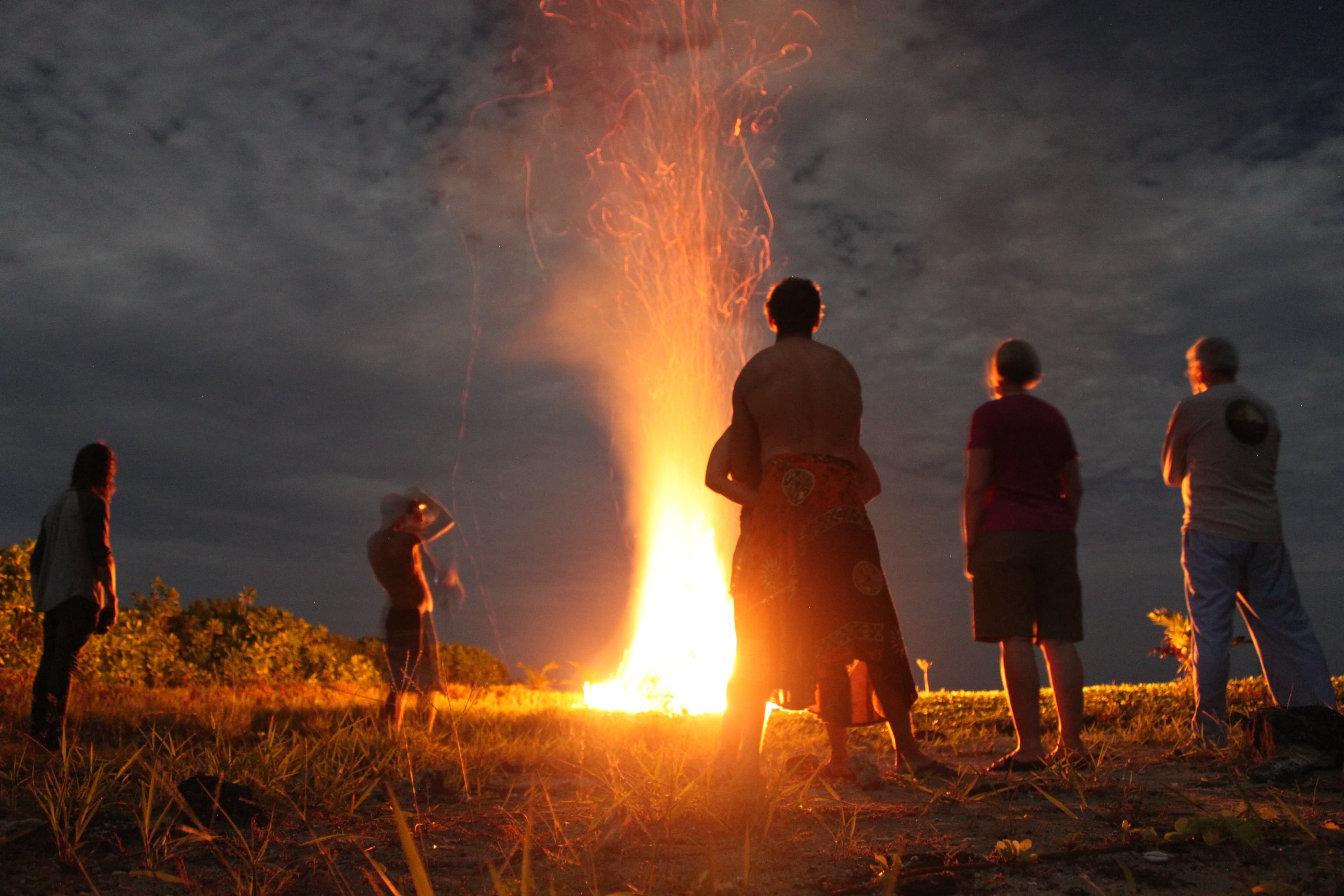 People standing around a beach fire at night on Asu Island