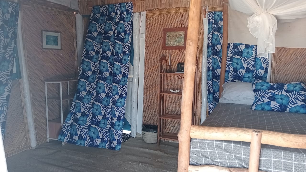 Room interior at Chez Andrea with reed walls, hibiscus curtains and two beds