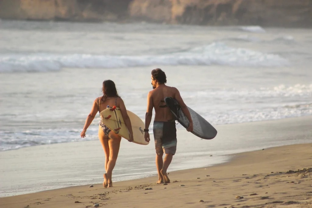Two surfers walking the sand at Las Tunas with their boards