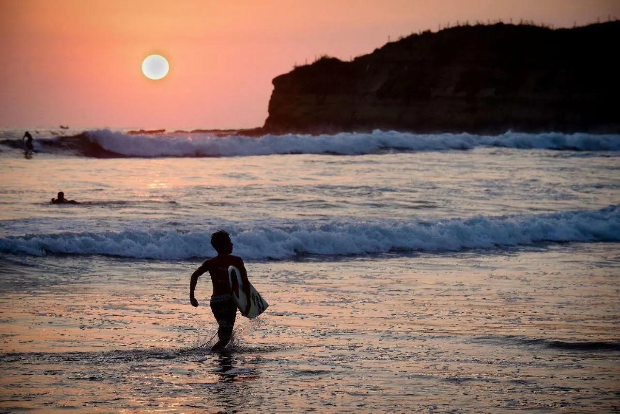 Surfer running down the beach at sunset, La Punta, Montañita
